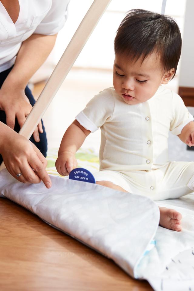 Close up of a child playing with the edge of the activity mat for the Lovevery Play Gym